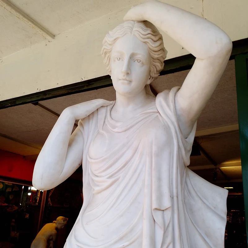 Large marble sculpture of a woman with flowers at her feet