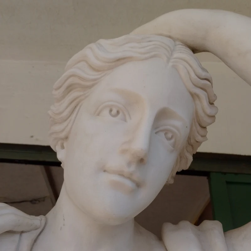Large marble sculpture of a woman with flowers at her feet