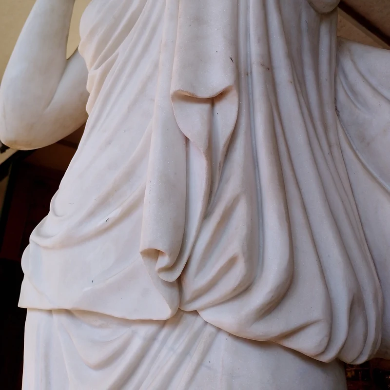 Large marble sculpture of a woman with flowers at her feet