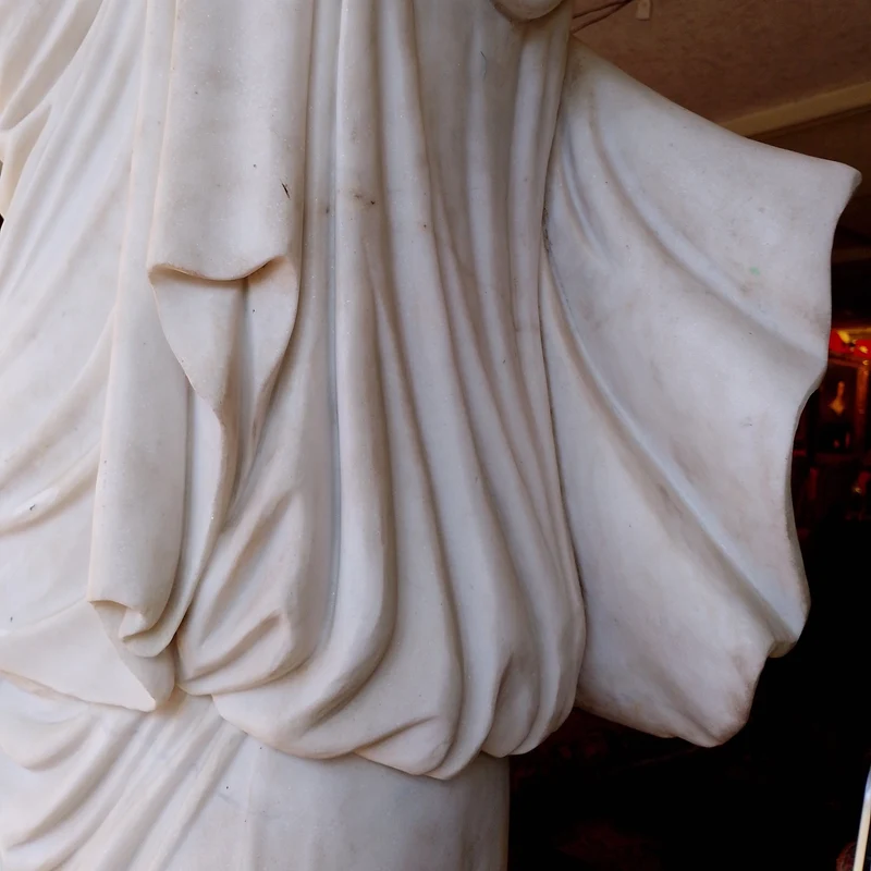 Large marble sculpture of a woman with flowers at her feet