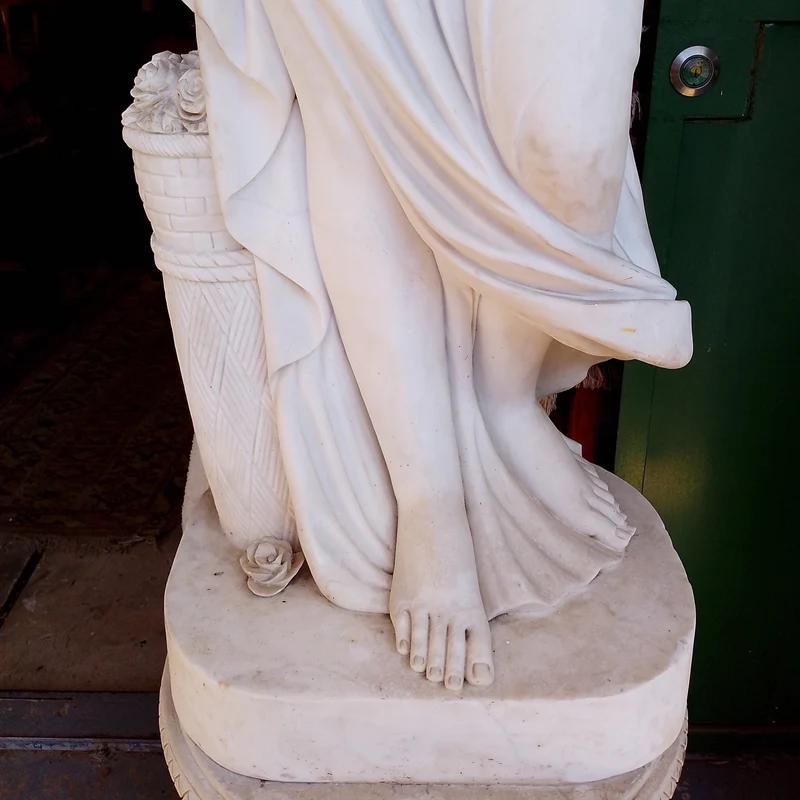 Large marble sculpture of a woman with flowers at her feet