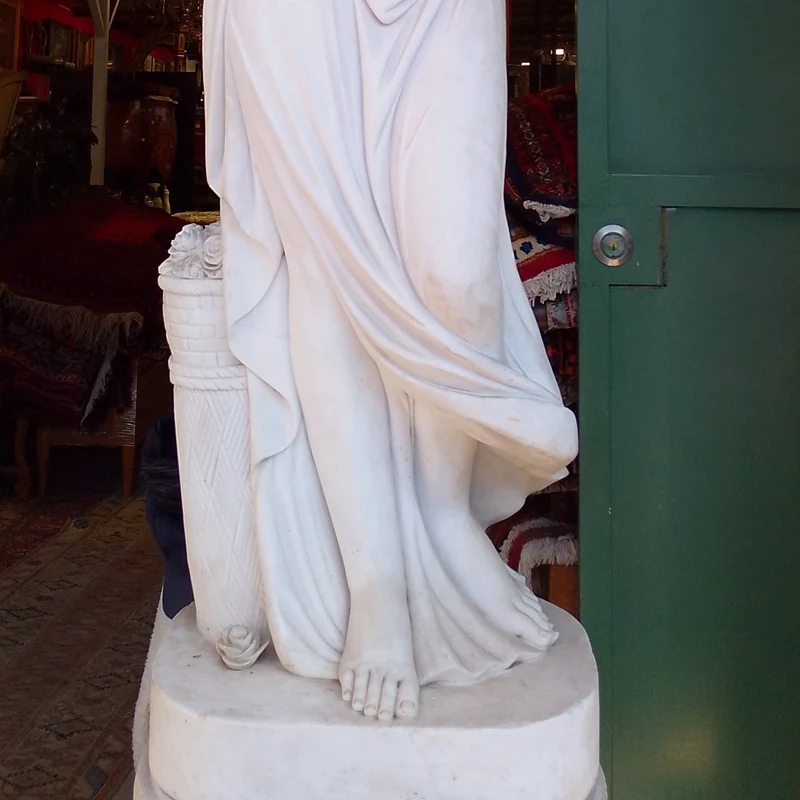 Large marble sculpture of a woman with flowers at her feet